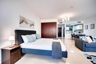 a bedroom with a large bed and a living room at Big sea view studio in JBR in Dubai