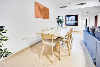 a dining room with a table and chairs and a blue couch at Nice and comfy 2BD apartment in Jbr in Dubai