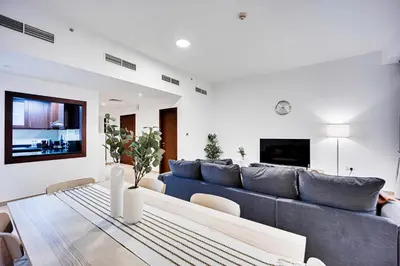 a living room with a blue couch and a table at Nice and comfy 2BD apartment in Jbr in Dubai