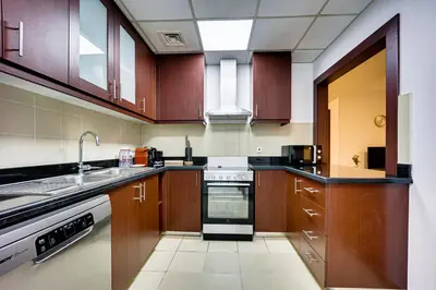 a kitchen with wooden cabinets and a sink and a stove at Nice and comfy 2BD apartment in Jbr in Dubai