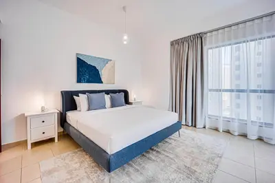 a bedroom with a bed and a large window at Nice and comfy 2BD apartment in Jbr in Dubai