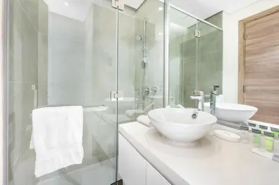 a bathroom with a white sink and a glass shower at ALiving Cozy Studio with Canal View I Studio One, Dubai Marina in Dubai