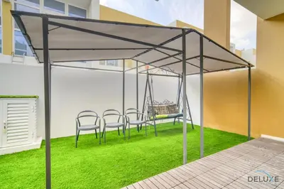 a patio with a swing and chairs on the grass at Alluring 3BR Townhouse at DAMAC Hills 2, Dubailand by Deluxe Holiday Homes in Dubai