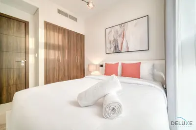 a white bedroom with a white bed with red pillows at Alluring 3BR Townhouse at DAMAC Hills 2, Dubailand by Deluxe Holiday Homes in Dubai