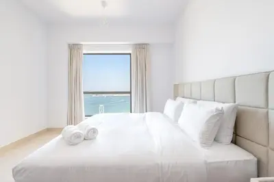 a bedroom with a bed with two towels on it at Deluxe Retreat In JBR - Million Dollar View - Balcony in Dubai