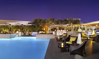 a swimming pool with chairs and tables at night at Fashion Avenue Dubai Mall Highest Floor Burj Khalifa View Residence- Formerly Address Dubai Mall in Dubai