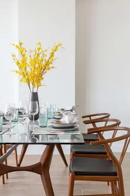 a dining room table with chairs and a vase with yellow flowers at Frank Porter - Al Nabat in Dubai