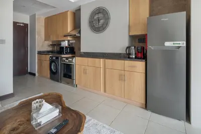 a kitchen with wooden cabinets and a refrigerator at Chic JLT Studio, Lake View, Pool, Metro Access in Dubai