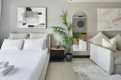 a bedroom with a white bed and a potted plant at Chic JLT Studio, Lake View, Pool, Metro Access in Dubai