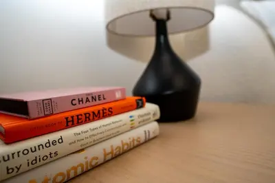a stack of books sitting on a table with a lamp at Majestay - Luxury Living in Dubai