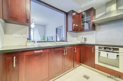 a kitchen with wooden cabinets and a large window at Harmonious 1BR at 29 BLVD Tower 1 Downtown Dubai by Deluxe Holiday Homes in Dubai