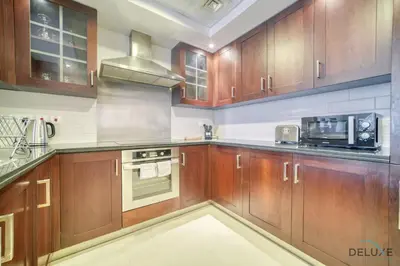 a kitchen with wooden cabinets and a stove top oven at Harmonious 1BR at 29 BLVD Tower 1 Downtown Dubai by Deluxe Holiday Homes in Dubai