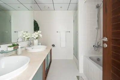a white bathroom with two sinks and a tub and a bath tubermott at Frank Porter - Al Sahab 2 in Dubai