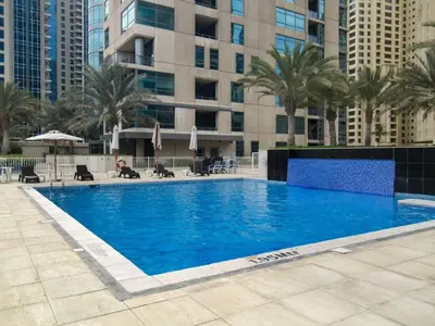 a large swimming pool with palm trees and buildings at Frank Porter - Al Sahab 2 in Dubai