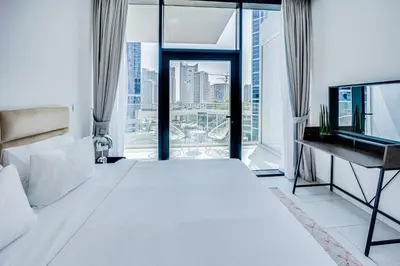a bedroom with a large white bed and a window at Stylish studio in Marquise Square Tower in Dubai