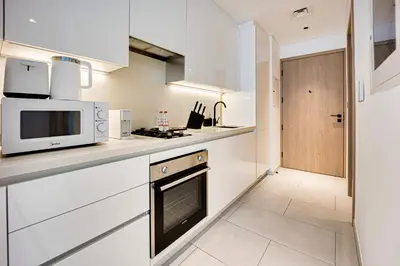 a kitchen with white cabinets and a microwave at Stylish studio in Marquise Square Tower in Dubai