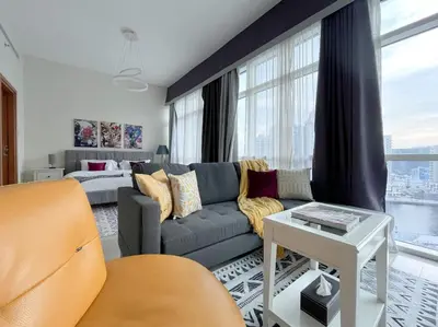 a living room with a couch and a bed at Trophy Stays - Vibrant Work-Friendly Studio in Business bay in Dubai