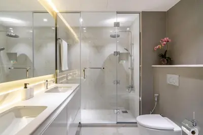 a bathroom with a shower and two sinks and a toilet at The Smart Concierge - Amwaj 4 in Dubai