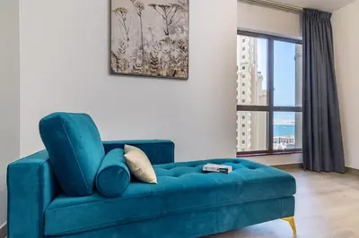 a blue couch in a living room with a window at The Smart Concierge - Amwaj 4 in Dubai