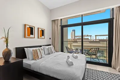 a bedroom with a bed and a large window at Mesmerizing nicely furnished studio in JVC in Dubai