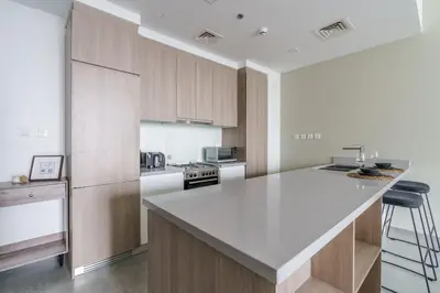 a kitchen with wooden cabinets and a white counter top at GuestReady - Modern Mirza with Marina View in Dubai