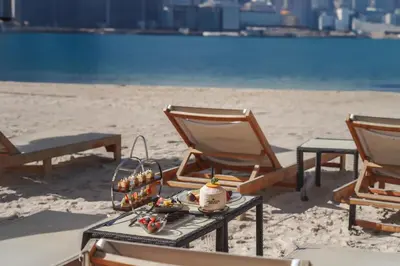 two chairs and a table on a beach with a tray of food at NH Collection Dubai The Palm in Dubai
