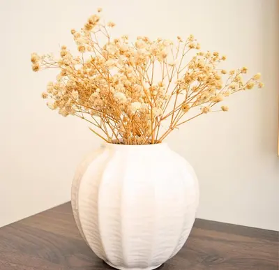 a white vase with flowers in it on a table at Perfect 1 Bedroom Boulevard,Fountain & Opera View in Dubai