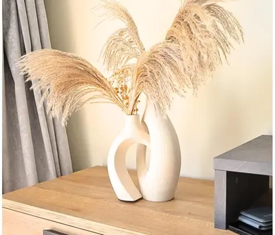 two white vases sitting on a table with grass at Perfect 1 Bedroom Boulevard,Fountain & Opera View in Dubai