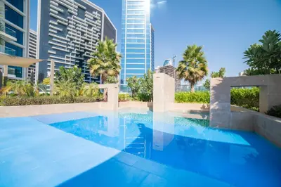 a swimming pool with palm trees and buildings at Vacay Lettings - Waterfront Studio with great Dubai Canal view in Dubai