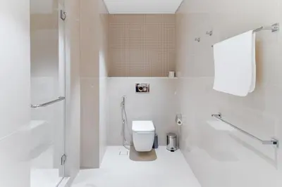 a white bathroom with a toilet and a shower at Holidays R Us Royal View in Dubai