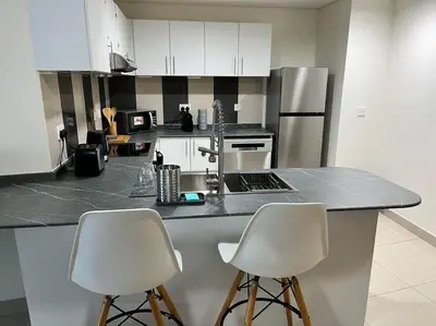a kitchen with two white chairs and a counter top at Ocean Heights - Spacious 1 Bedroom Apartment with Sea View, Gym & Free Parking in Dubai