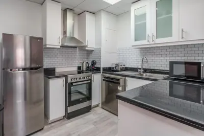 a kitchen with stainless steel appliances and white cabinets at GuestReady - Lux Aeterna in JBR in Dubai