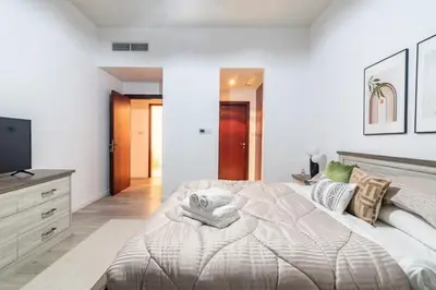 a white bedroom with a large bed and a flat screen tv at GuestReady - Lux Aeterna in JBR in Dubai