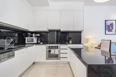 a white kitchen with black and white appliances at Ornate 1BR in The Address Residences Dubai Marina by Deluxe Holiday Homes in Dubai