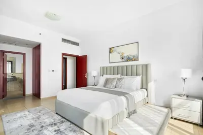 a white bedroom with a large bed and a rug at Beautiful Sea and Marina View - Premium 2BR in JBR in Dubai