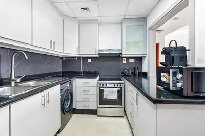 a kitchen with white cabinets and black counter tops at Beautiful Sea and Marina View - Premium 2BR in JBR in Dubai