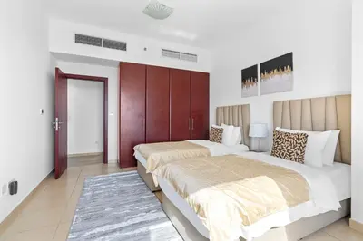 two beds in a room with white walls at Beautiful Sea and Marina View - Premium 2BR in JBR in Dubai