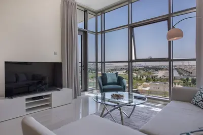 a living room with a couch and a glass table at Bright and spacious apartment in DAMAC HILLS in Dubai