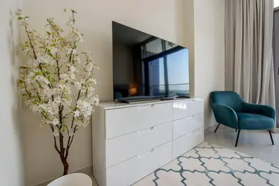 a living room with a tv and a blue chair at Bright and spacious apartment in DAMAC HILLS in Dubai