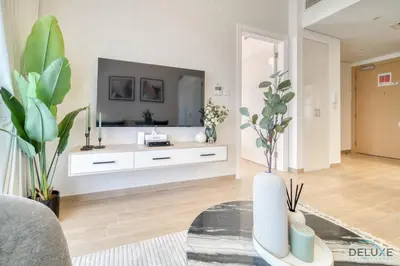 a living room with a tv on a wall at Serene 2BR at The Nook Wasl Gate Jebel Ali by Deluxe Holiday Homes in Dubai