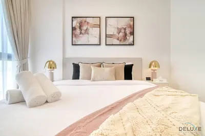 a bedroom with a large white bed with three paintings on the wall at Serene 2BR at The Nook Wasl Gate Jebel Ali by Deluxe Holiday Homes in Dubai