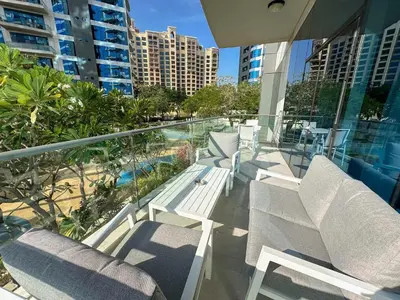 a balcony with chairs and a swimming pool and some buildings at Sunset view apartment in Oceana in Dubai