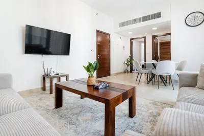a living room with a table and a tv on a wall at Modern 1BR in Dubai Marina Near Metro & Beach in Dubai