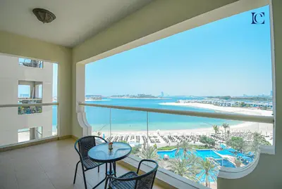 a balcony with a table and chairs and a view of the beach at Luxury Escapes - Palm Jumeirah's Spectacular Ocean-View Apartment - NABAT in Dubai