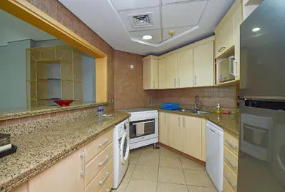 a large kitchen with white appliances and wooden cabinets at Luxury Escapes - Palm Jumeirah's Spectacular Ocean-View Apartment - NABAT in Dubai