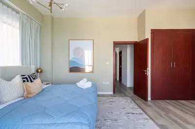 a bedroom with a blue bed and a large window at GuestReady - Sea la Vie - Lux in JBR in Dubai