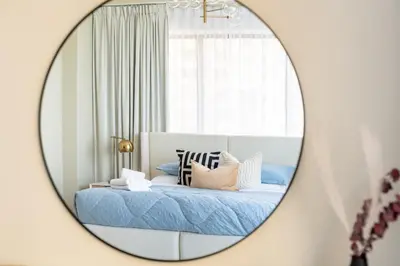 a mirror reflecting a bed with blue sheets and pillows at GuestReady - Sea la Vie - Lux in JBR in Dubai