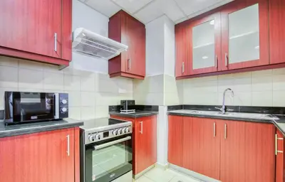 a kitchen with red cabinets and a microwave at 360 Vacation - Spacious 3BR Close to the Beach I Rimal1 JBR in Dubai