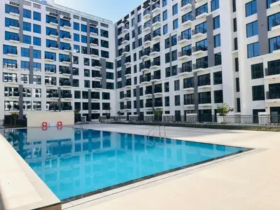 a swimming pool in front of two tall buildings at BNew Chic 1BR Apt Near Trump Golf w Pool and Gym in Dubai