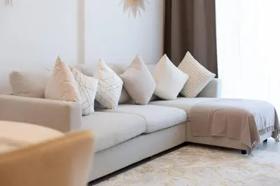 a living room with a couch with pillows on it at BNew Chic 1BR Apt Near Trump Golf w Pool and Gym in Dubai